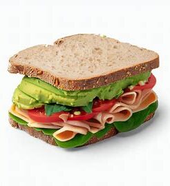 whole wheat sandwich with deli turkey meat, avocado, tomato and spinach.